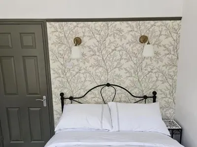 a bedroom with a bed with a floral wallpaper at Shakespeare's Snug in Prescot