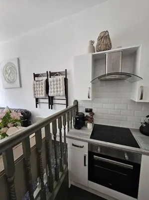 a kitchen with a stove top oven next to a staircase at Shakespeare's Snug in Prescot