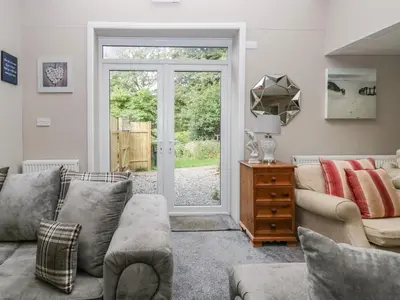 a living room with a couch and a sliding glass door at Clarence House in Dalton in Furness