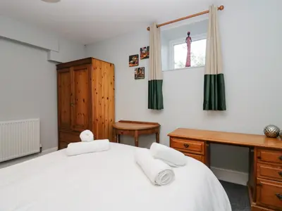 a bedroom with a white bed and a desk and a window at Clarence House in Dalton in Furness