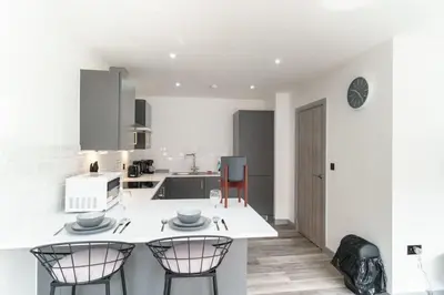a white kitchen with two chairs and a counter at Modern 1 Bedroom Apartment in Preston Centre in Preston