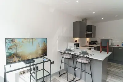 a kitchen with two bar stools and a counter at Modern 1 Bedroom Apartment in Preston Centre in Preston
