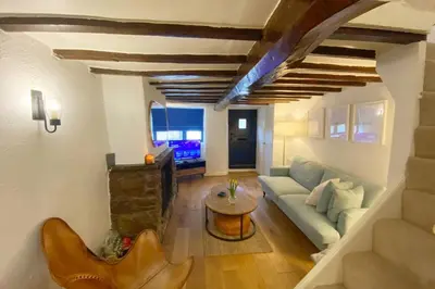 a living room with a couch and a table at 1750's cottage with open fire and beams in Upholland