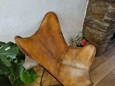 a brown leather chair sitting next to a brick wall at 1750's cottage with open fire and beams in Upholland