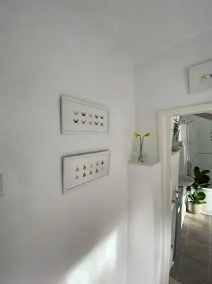a white room with three pictures on the wall at 1750's cottage with open fire and beams in Upholland