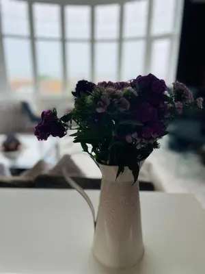 a white vase filled with purple flowers on a table at 1 Bedroom Sea side luxury in New Brighton