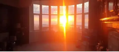 a sunset in a window with the sun shining through at 1 Bedroom Sea side luxury in New Brighton