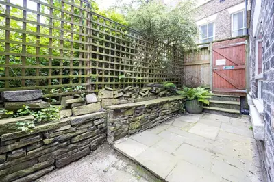 a garden with a stone wall and a fence at GuestReady - Charming haven in Knowledge Quarter in Liverpool