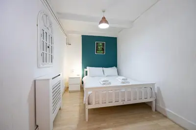 a bedroom with a white bed and a blue wall at GuestReady - Charming haven in Knowledge Quarter in Liverpool
