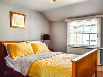 a bedroom with a bed with yellow sheets and a window at Waterloo Sunset in Bootle