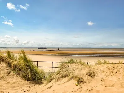 a beach with a fence in the sand at Waterloo Sunset in Bootle