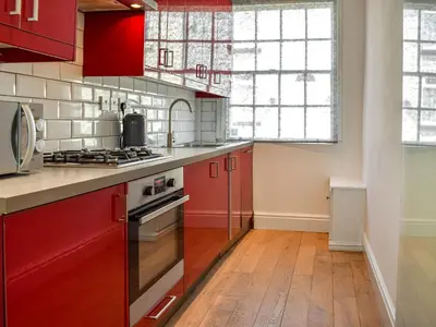 a kitchen with red cabinets and a stove top oven at Waterloo Sunset in Bootle