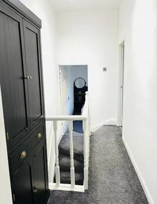 a hallway with a staircase with a black cabinet at Stylish 3BR house near Liverpool Football Club in Liverpool