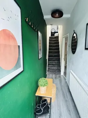 a hallway with a green wall with a stair case at Stylish 3BR house near Liverpool Football Club in Liverpool