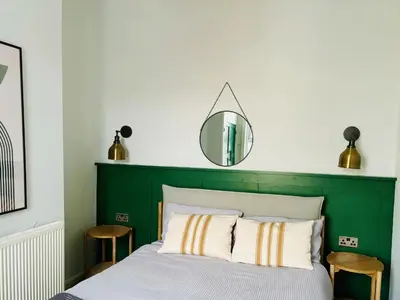 a bedroom with a green headboard and a mirror at Stylish 3BR house near Liverpool Football Club in Liverpool