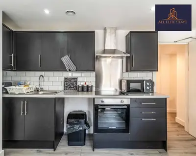 a kitchen with black cabinets and a sink and a microwave at Swan House Apartment 2 - 1 Bed Apartment - Sleeps up to 4 - Free Parking - Liverpool - close to city centre - By ALL ELITE STAYS in Liverpool