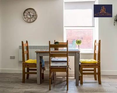 a dining room table with chairs and a clock on the wall at Swan House Apartment 5 - 2 Bed Apartment - Sleeps 6 - Free Parking - Liverpool - close to city centre - By ALL ELITE STAYS in Liverpool