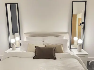 a white bed with pillows and mirrors in a bedroom at Elegant and Sophisticated, and we mean it! in Liverpool