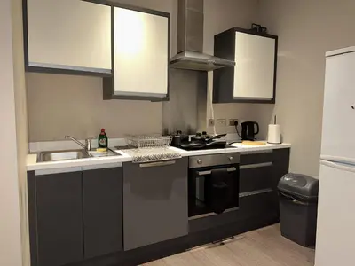 a kitchen with black and white cabinets and a sink at Elegant and Sophisticated, and we mean it! in Liverpool
