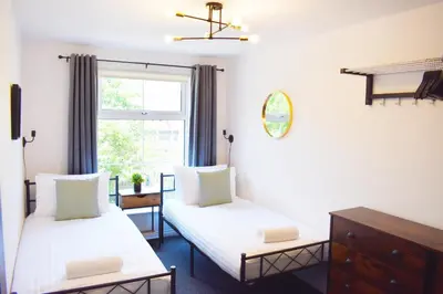two beds in a room with a window at City Center Apartments FREE PARKING in Liverpool