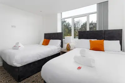 a bedroom with two beds with orange and white pillows at Flatzy - 16 Guests 4 En-suite Central Apartment B in Liverpool