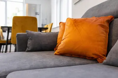 an orange pillow sitting on a gray couch at Flatzy - 16 Guests 4 En-suite Central Apartment B in Liverpool