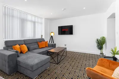 a living room with a gray couch and orange pillows at Flatzy - 16 Guests 4 En-suite Central Apartment B in Liverpool