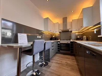 a kitchen with white cabinets and a table and chairs at Franks Apt 1 - Outdoor Courtyard - Sleeps 6 in Blackpool