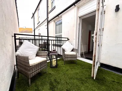 a balcony with two chairs and a table on the grass at Franks Apt 2 - Outdoor Balconies - Sleeps 8 in Blackpool