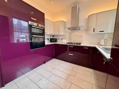 a large kitchen with purple cabinets and a sink at Franks Apt 2 - Outdoor Balconies - Sleeps 8 in Blackpool