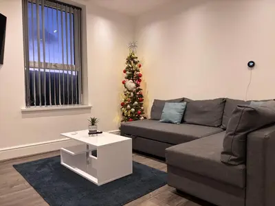 a living room with a couch and a christmas tree at Franks Apt 3 - Sleeps 4 in Blackpool