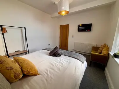 a bedroom with a large white bed and a chair at Franks Apt 3 - Sleeps 4 in Blackpool