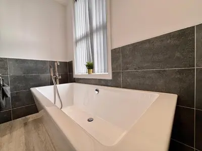 a white bath tub in a bathroom with a window at Franks Apt 4 - Roof Terrace - Sleeps 6 in Blackpool
