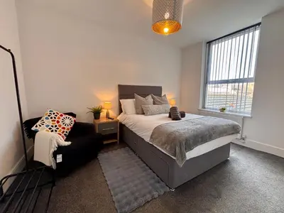 a bedroom with a bed and a chair and a window at Franks Apt 4 - Roof Terrace - Sleeps 6 in Blackpool