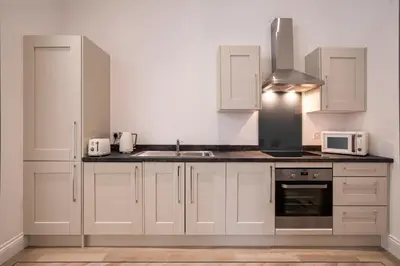 a kitchen with white cabinets and a sink and a microwave at The Castle Collection - 5 Union Court in Liverpool