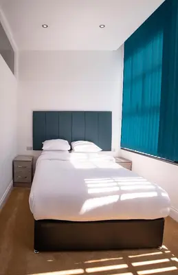 a bedroom with a large white bed with a blue headboard at The Castle Collection - 5 Union Court in Liverpool