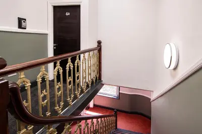 a staircase with a wooden railing and a black door at The Castle Collection - 5 Union Court in Liverpool