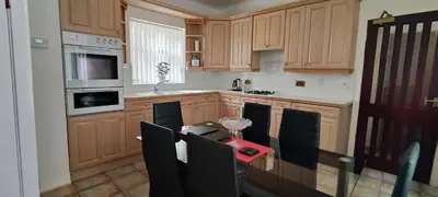 a kitchen with wooden cabinets and a table with chairs at Lawnswood Apartments in Blackpool