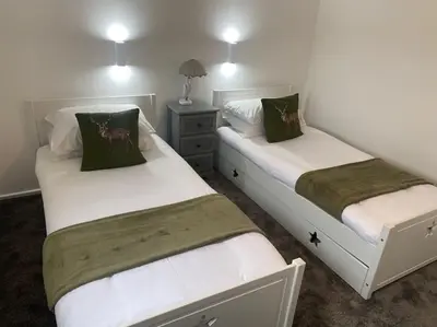 two beds in a small room with white walls at Hideaway Lodge in Carnforth