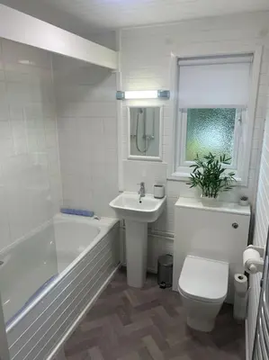 a white bathroom with a sink and a toilet and a tub at Hideaway Lodge in Carnforth