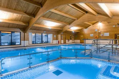 a large indoor swimming pool with a wooden ceiling at Hideaway Lodge in Carnforth
