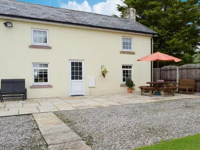 a white house with a patio and a red umbrella at West Boundary Farm Cottage 1 in Pilling