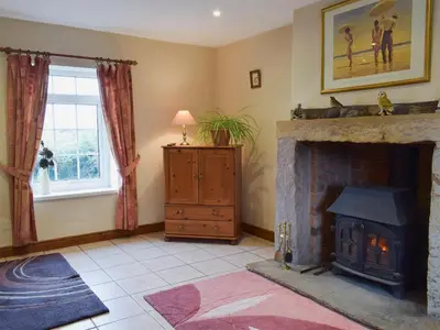 a living room with a stone fireplace and a window at West Boundary Farm Cottage 1 in Pilling