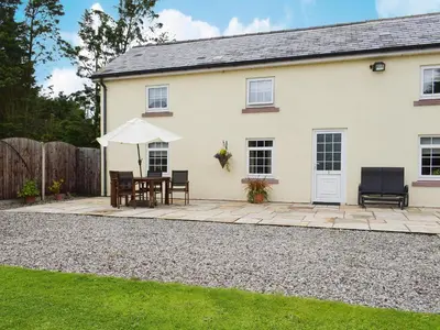 a white house with a table and an umbrella at West Boundary Farm Cottage 2 in Pilling