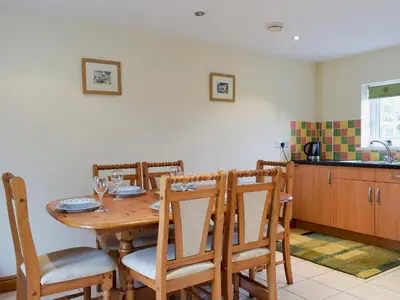 a dining room table with chairs and a kitchen at West Boundary Farm Cottage 2 in Pilling