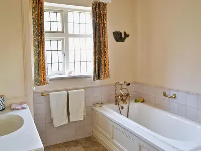 a bathroom with a tub and a sink and a window at Ivy House in Saint Annes on the Sea