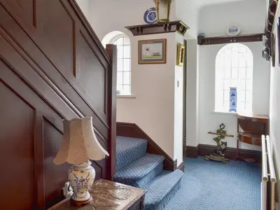 a hallway with stairs and a lamp on a table at Ivy House in Saint Annes on the Sea