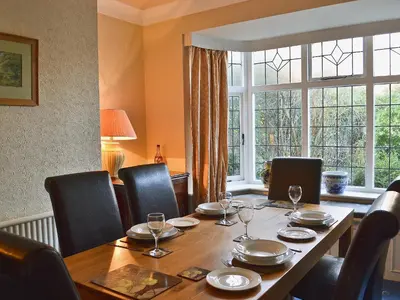 a dining room table with chairs and a large window at Ivy House in Saint Annes on the Sea