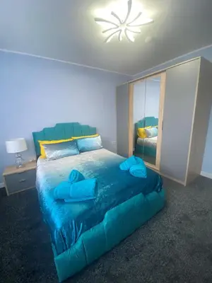 a bedroom with a blue bed and a mirror at Jackson Holiday Apartments in Blackpool