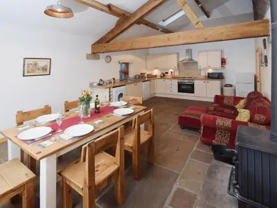 a kitchen and living room with a wooden table and chairs at Bramble Cottage - 27978 in Whalley
